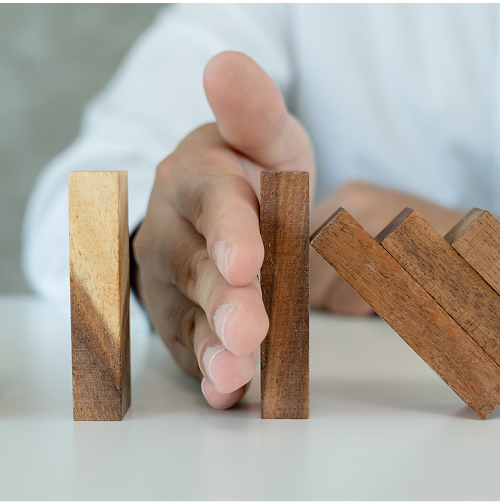 a man using his hand to stop the flow of dominoes falling